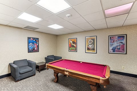 A room with a pool table and three framed pictures on the wall.